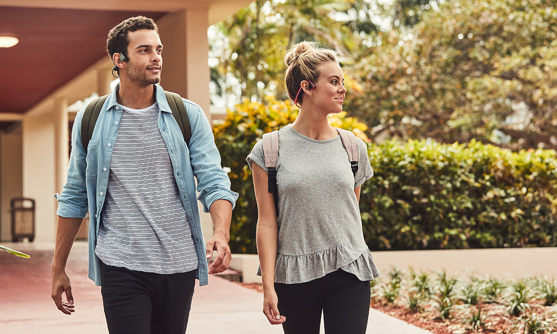 Man and woman walking while wearing AfterShokz