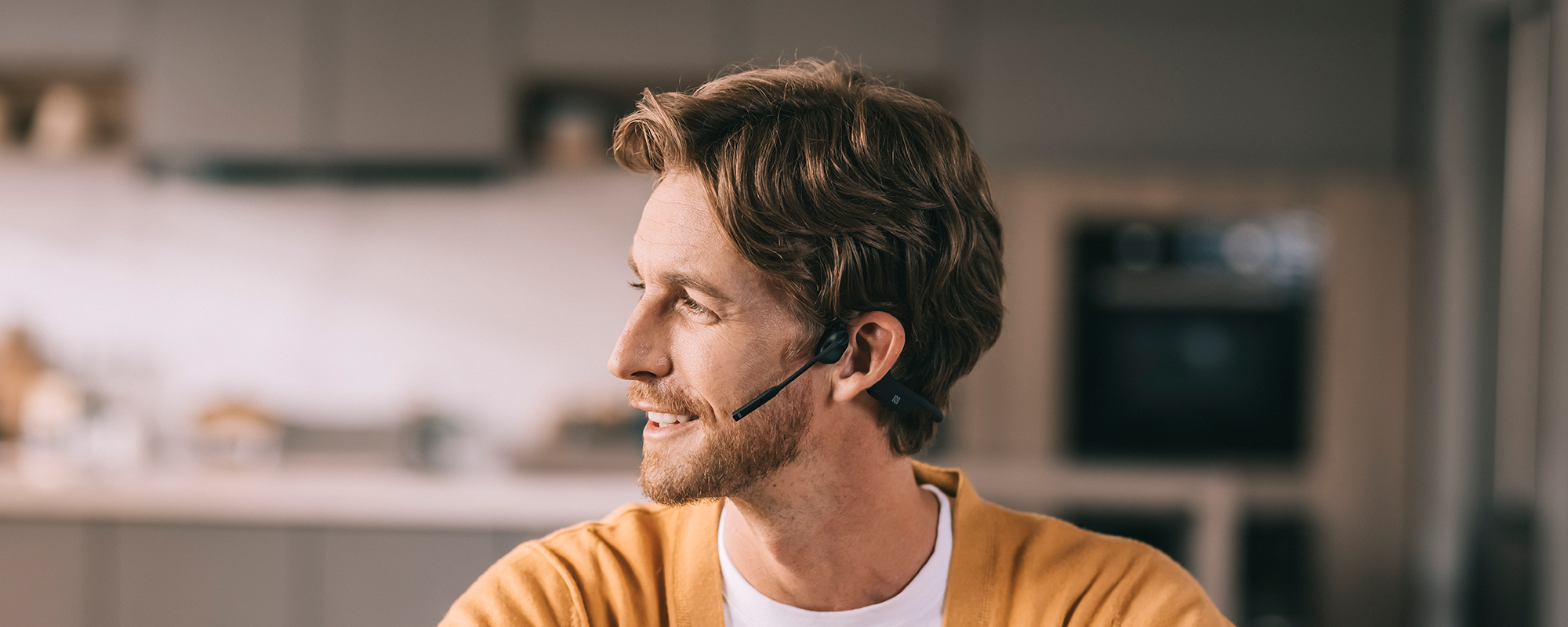 Image of man working from home and wearing Shokz OpenComm UC wireless headset