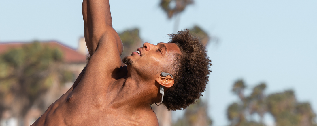 Photo of a man working out on the beach while wearing Shokz OpenRun wireless headphones