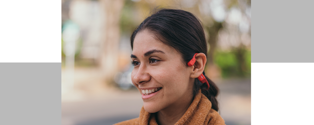 Up-close image of Latina woman smiling and wearing Shokz OpenRun wireless headphones