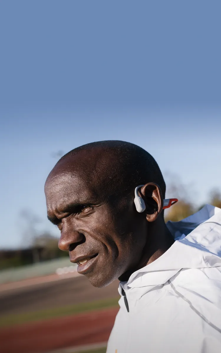 Eliud Kipchoge wears Shokz sports headphones, known for their comfort, lightweight design, and safety.