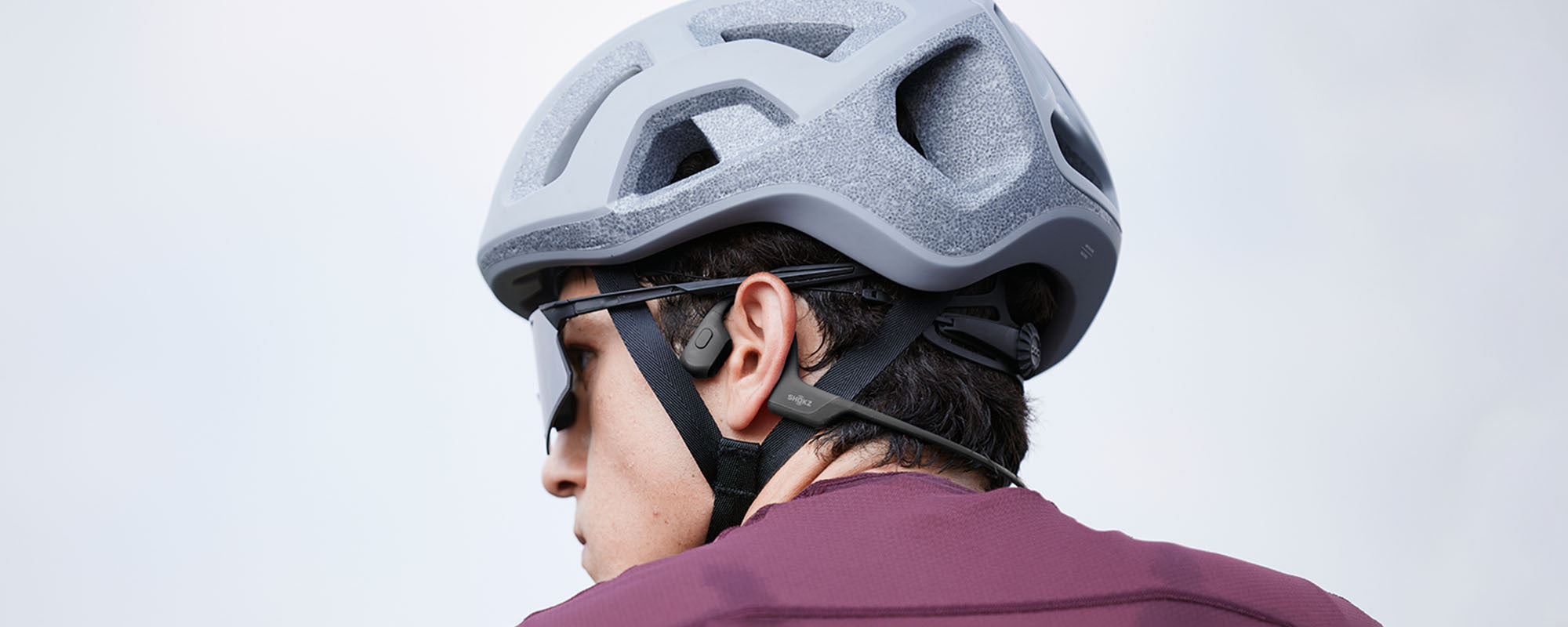 Man wearing bike helmet and OpenRun Pro wireless headphones