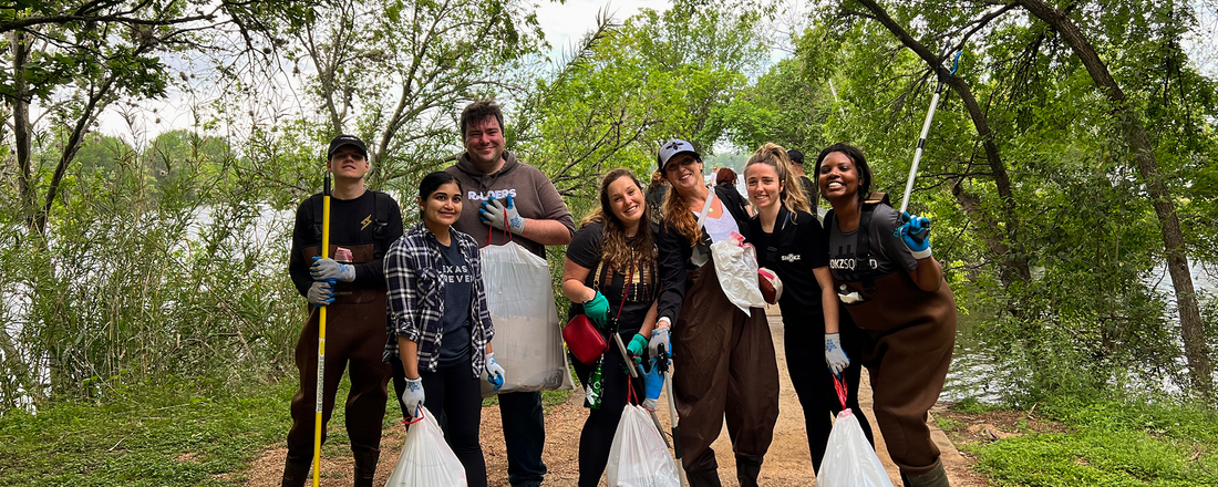 Group of Shokz team members in yard overalls and carrying trash bags cleaning up a local trail