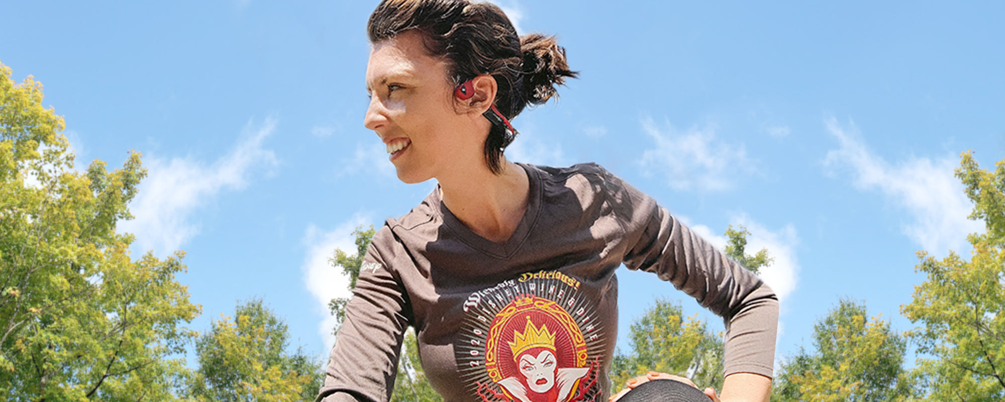 Woman wearing runDisney shirt and AfterShokz Air wireless headphones.