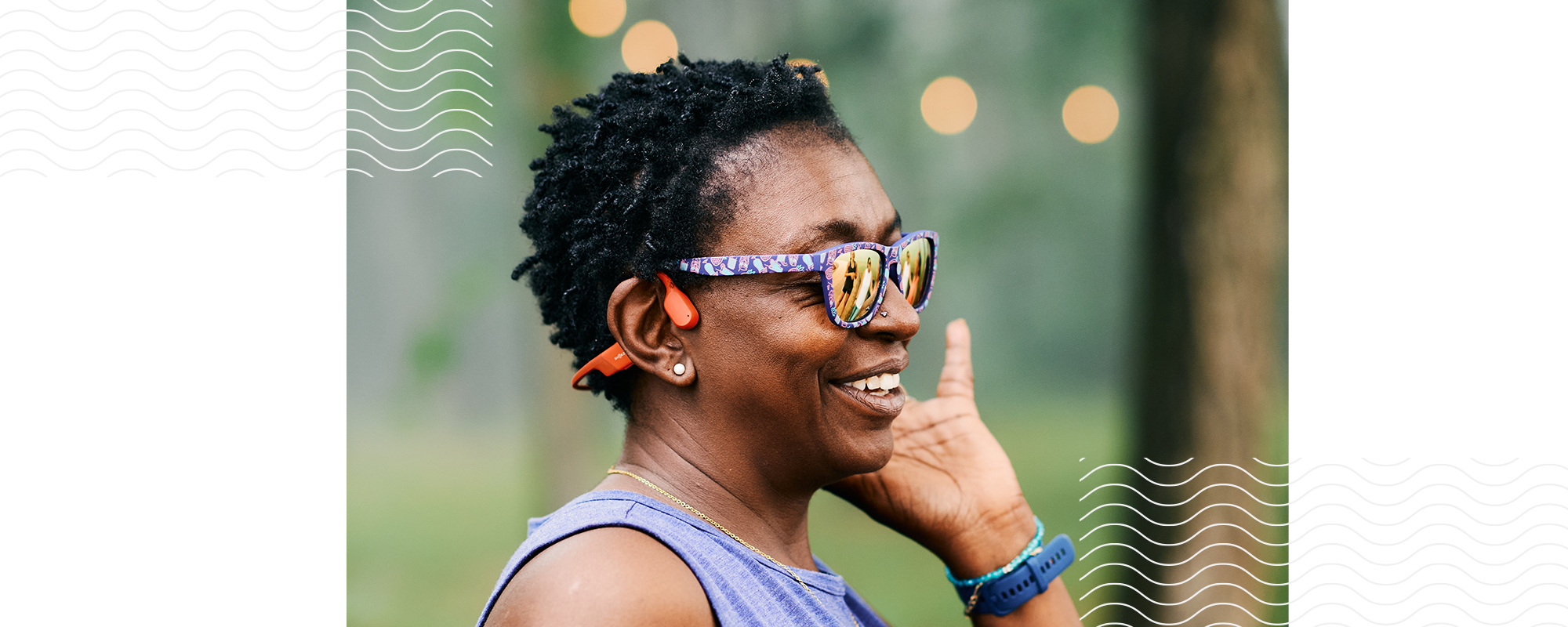 Close-up image of an African American woman wearing sunglasses and OpenRun wireless headphones