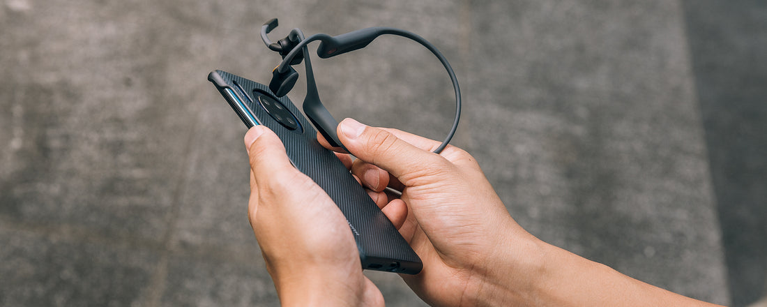 Person using NFC Pairing to sync AfterShokz OpenCom headset to device