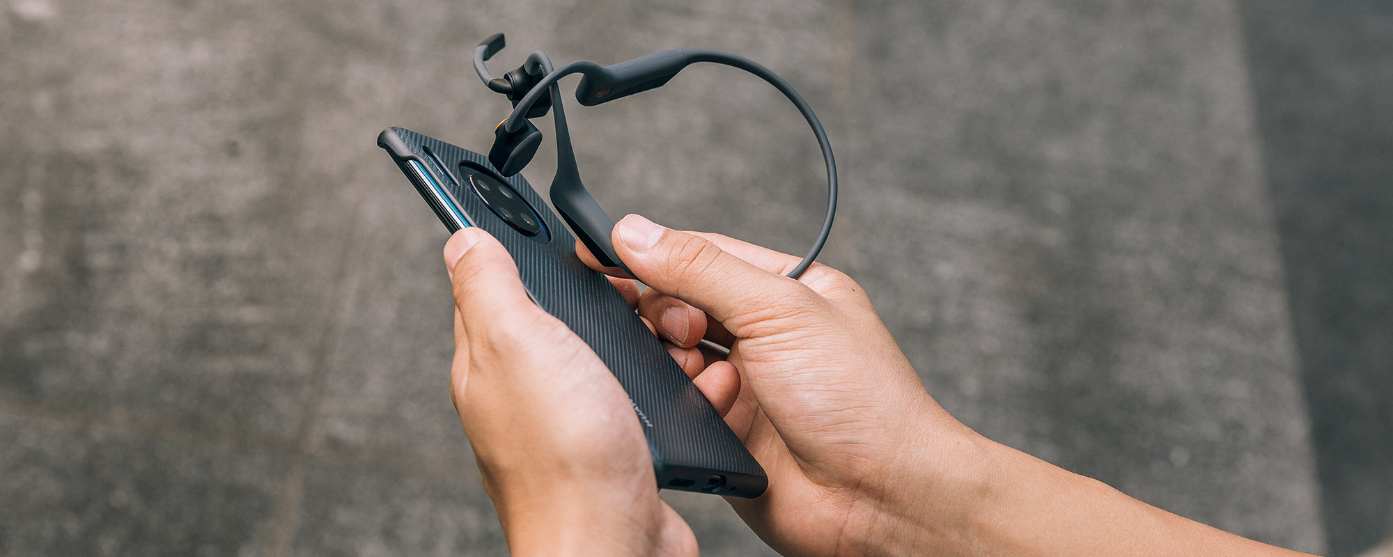 Person using NFC Pairing to sync AfterShokz OpenCom headset to device