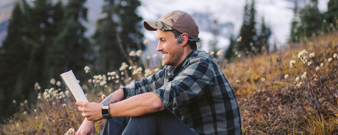 Man meditating outdoors in forrest wearing AfterShokz Air headphones