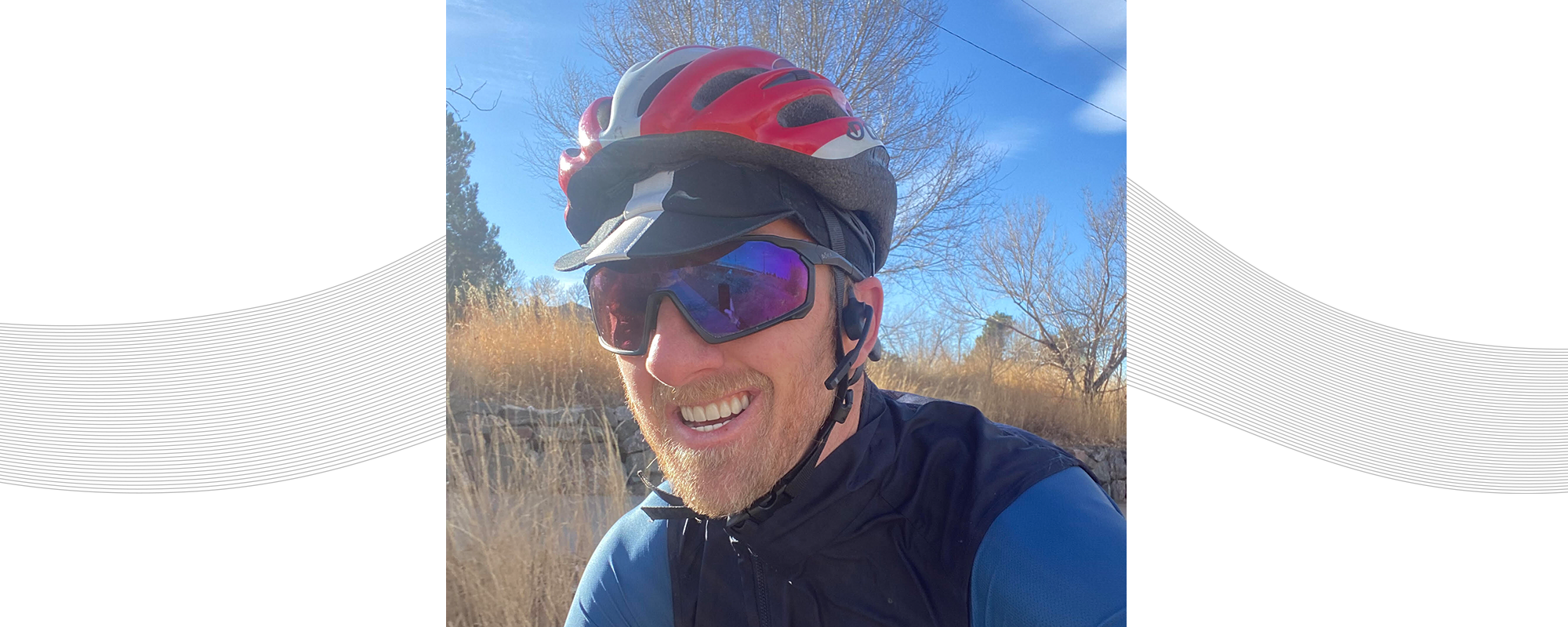 Dr. Justin Ross riding his bike while wearing helmet and AfterShokz Aeropex headphones