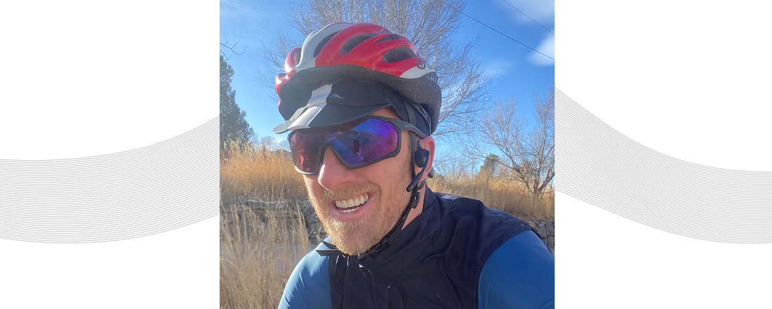 Dr. Justin Ross riding his bike while wearing helmet and AfterShokz Aeropex headphones