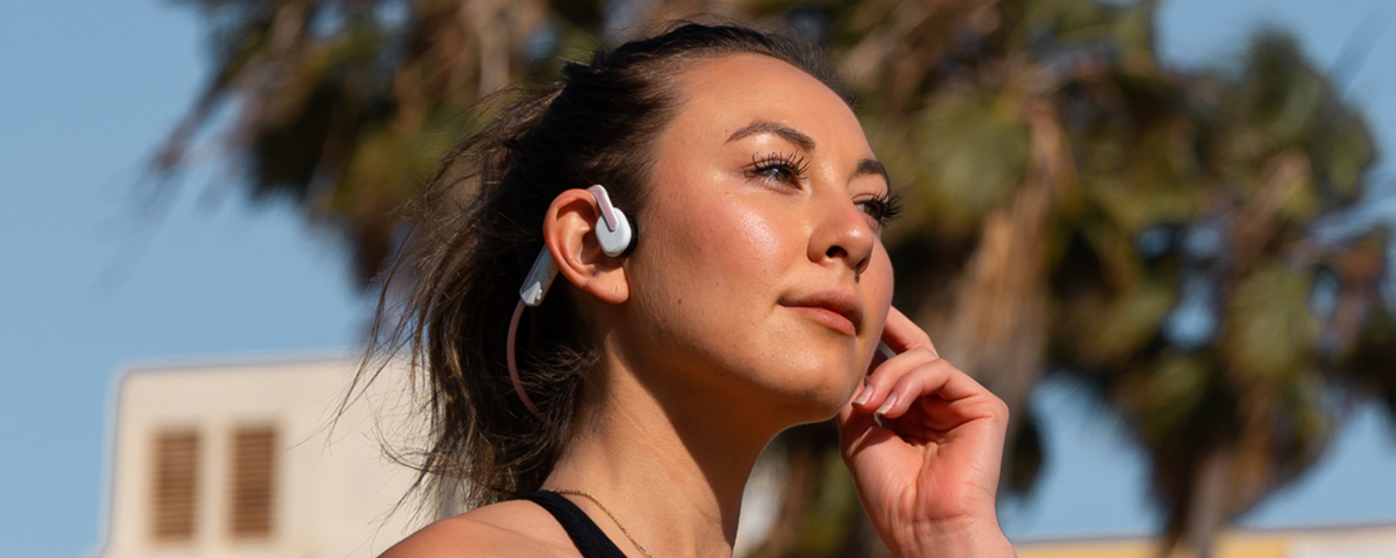 Woman running outside wearing AfterShokz OpenMove wireless headphones
