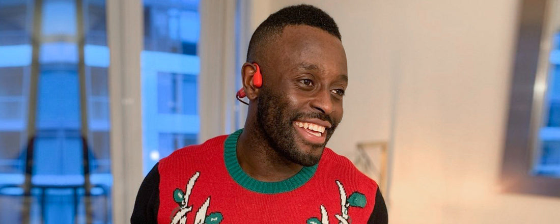 Man wearing Chritmas sweater and AfterShokz Aeropex wireless headphones