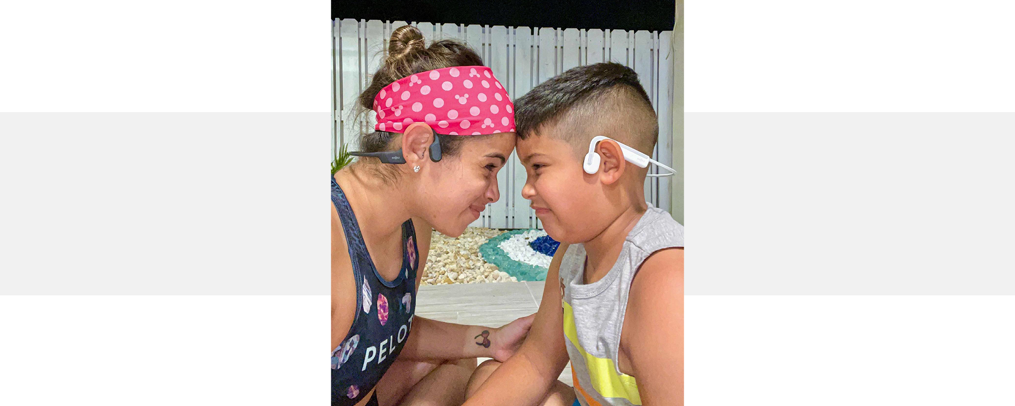 Mother wearing OpenRun wireless headphones with son wearing OpenMove headphones