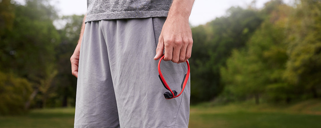 Person holding AfterShokz Titanium wireless headphones