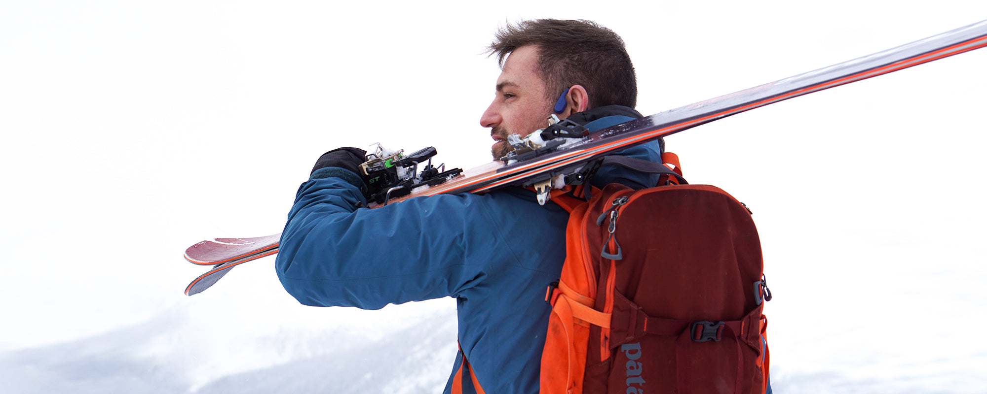 Man carrying skiis in the mountains while wearing Aeropex wireless headphones